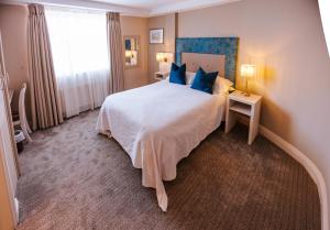 a bedroom with a large white bed with blue pillows at Stella Maris Hotel in Kilkee