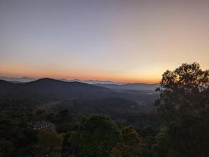 a sunset over the mountains with a house in the foreground at Oxyrich Business Class Hotel in Madikeri