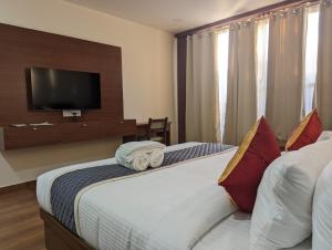 a bedroom with two beds and a flat screen tv at Oxyrich Business Class Hotel in Madikeri