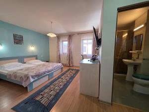 a bedroom with a bed and a bathroom with a sink at Pensiunea Maria , Floresti in Floreşti