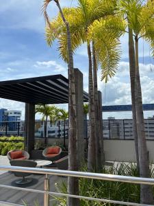 a patio with palm trees and a table and chairs at TIME Ponta Verde in Maceió