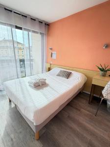 a large bed in a room with an orange wall at Hotel Bains Sarrailh in Dax