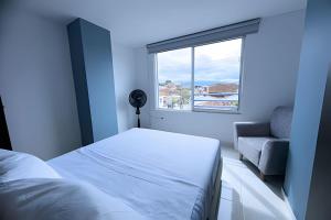 a bedroom with a bed and a window and a couch at amplio y lujoso apartasuite en el centro in Cartago