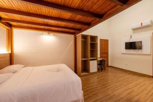 a bedroom with a white bed and a tv at Vektor Hotéis - Unidade Mariana in Mariana