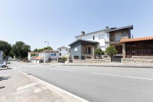 an empty street with houses and a car on the road at Trajadinha do Lima Apart in Ponte de Lima