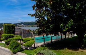a swimming pool in a garden with a lake in the background at Villa Maria Caetana in Frazão