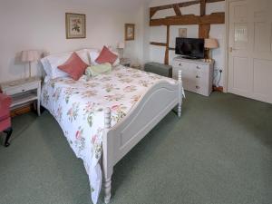 a bedroom with a white bed and a television at Howards End in Middleton on the Hill