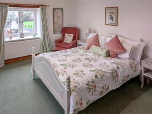 a bedroom with a white bed and a red chair at Howards End in Middleton on the Hill