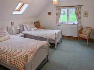 a bedroom with two beds and a chair and a window at Howards End in Middleton on the Hill