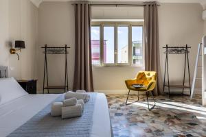 a bedroom with a large bed and a yellow chair at Lorixedda Rooms in Quartu SantʼElena