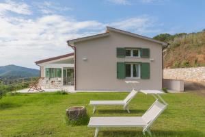 a house with two lounge chairs in front of it at Villa Belvedere - Helloelba in Santa Caterina