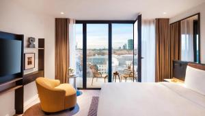 a hotel room with a large bed and a balcony at Kennedy 89 Hotel Frankfurt, part of Hyatt in Frankfurt