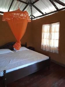 a bedroom with a bed with an orange curtain at Morakanda Estate in Kahaduwa