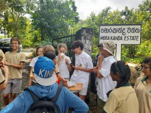 a group of young people standing around a sign at Morakanda Estate in Kahaduwa