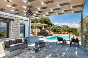a patio with a couch and a table and a pool at Villa Loulou by Villa Plus in Nikiana