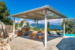 a pavilion with a fireplace and a table and chairs at Villa Loulou by Villa Plus in Nikiana