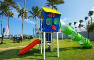 a playground with a slide in a park with palm trees at Gav Muro Alto Resort below average rate in Ipojuca