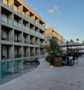 a building with a swimming pool next to a hotel at Gav Muro Alto Resort below average rate in Ipojuca