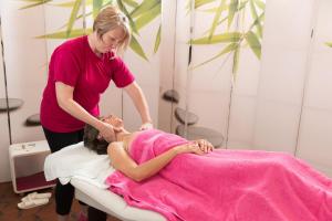 a woman in a pink dress laying on a bed at Hotel Bains Sarrailh in Dax