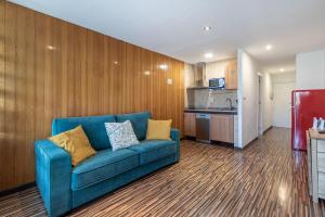 a living room with a blue couch and a kitchen at Sueño blanco in Sierra Nevada