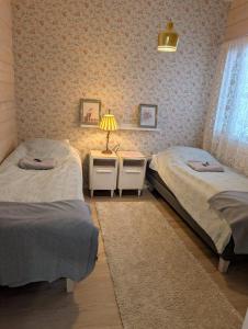 a bedroom with two beds and a lamp in it at Lake Norva Lodge in Saarenkylä
