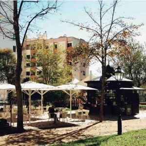 a cafe with tables and umbrellas in a park at Low Cost University Privado in Lisbon