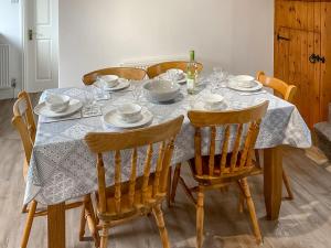 a dining room table with a white table cloth and chairs at Mistletoe Cottage - Uk50581 in Burnham on Sea
