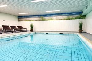 a swimming pool with blue tiles in a building at Norderhoog-Whg-45-2-OG-O-Wohnung-45 in Westerland