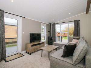 a living room with a couch and a flat screen tv at Poppy in Leominster