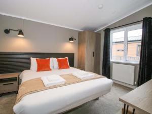 a bedroom with a large bed with orange pillows at Poppy in Leominster