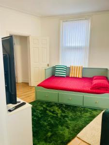 a bedroom with a green bed with a red couch at Cozy Cottage in Liverpool