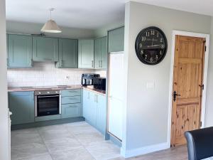 a kitchen with green cabinets and a clock on the wall at Clones Town House in Cluain Eois