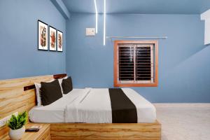a bedroom with a bed with blue walls and a window at Super Hotel O Daysinn Premium in Bhubaneshwar +26 photos