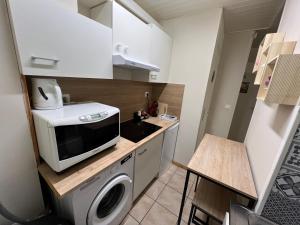 a small kitchen with a microwave and a washing machine at Le Nid du Centre in Anzin