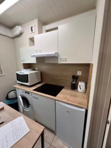 a small kitchen with white cabinets and a microwave at Le Nid du Centre in Anzin +4 photos
