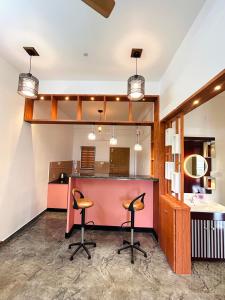 a kitchen with two bar stools and a counter at Flymount Homestay in Vagamon