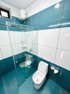 a bathroom with a toilet and a glass shower at Flymount Homestay in Vagamon