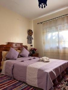 a bedroom with a large bed with purple sheets and a window at Casa laila in Chefchaouen