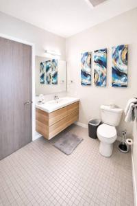a bathroom with a sink and a toilet and paintings at Cobalt Cove (132) in Des Moines +31 photos