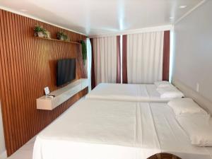 a hotel room with two beds and a tv at Flat em Cabo Branco - Blue Sunset in João Pessoa
