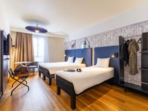 a hotel room with two beds and a couch at ibis Dunkerque in Dunkerque