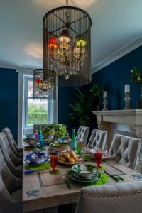 a dining room with a table with food and a chandelier at The Painted Cow in Beattock
