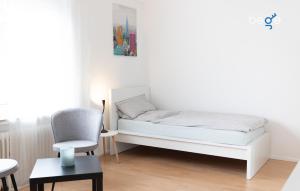 a white bedroom with a bed and a chair at BEGE APARTMENTS ComfortLoft in Unna