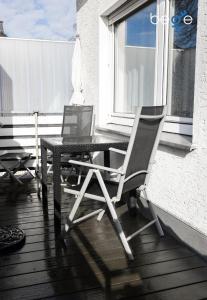 two chairs and a table on a porch with a window at BEGE APARTMENTS ComfortLoft in Unna