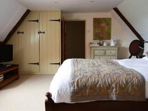 a bedroom with a bed and a television in it at Sutherland House in Southwold