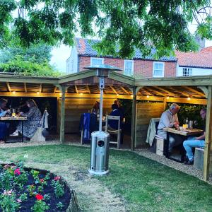 a group of people sitting at tables under a pergola at Sutherland House in Southwold +15 photos
