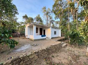 a small white house with a stone wall at Sree vinayaka homestay in Vagamon