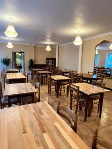 a restaurant with wooden tables and chairs and lights at Hôtel Le Square in Capvern +7 photos