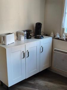 a kitchen with white cabinets with appliances on it at Studio 4 places - Centre-ville in Ax-les-Thermes