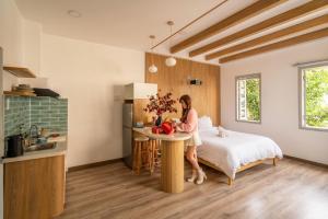 a woman is sitting on a bed in a kitchen at Chạm's Hotel & Homestay in Ho Chi Minh City